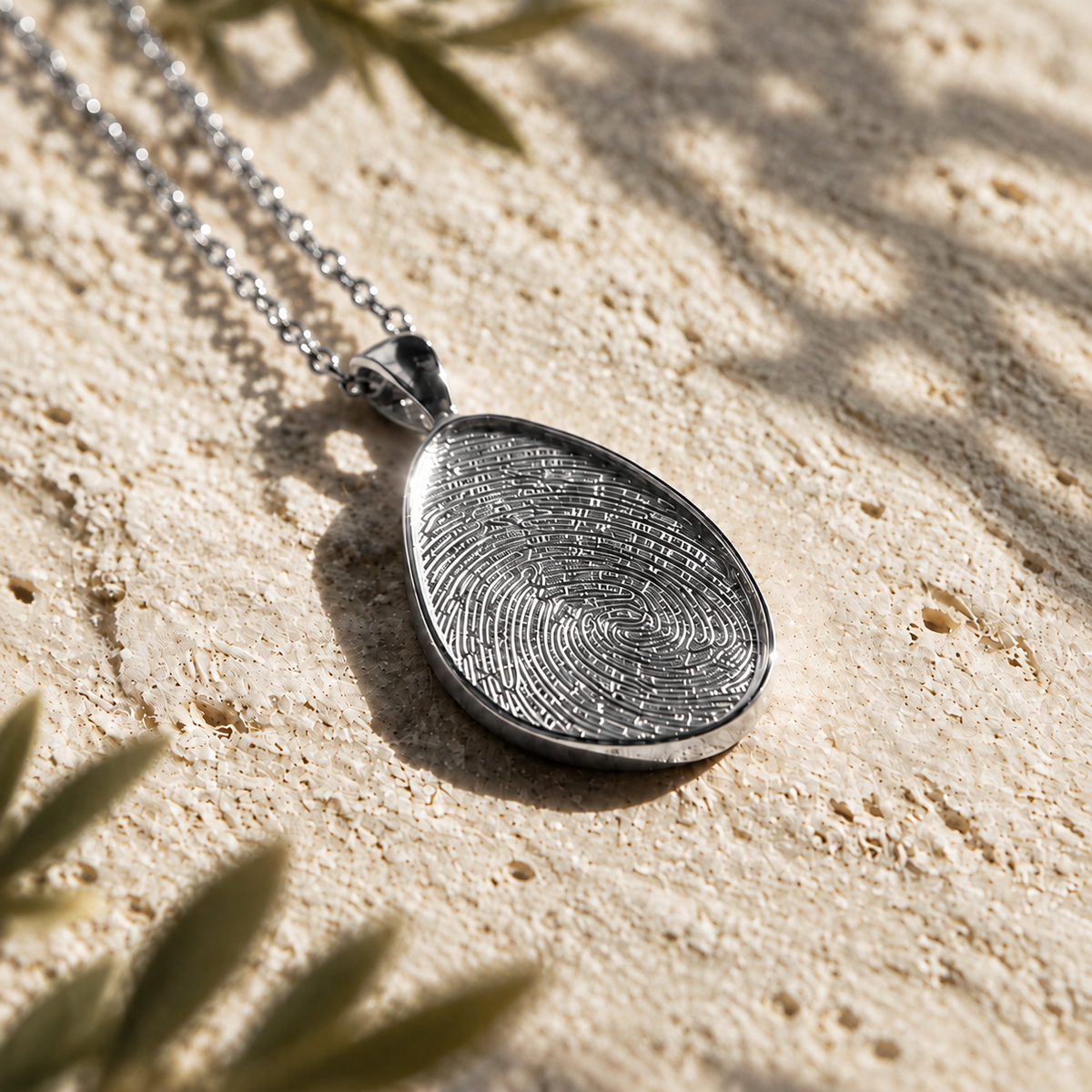 Silver fingerprint pendant and chain on cream textured stone