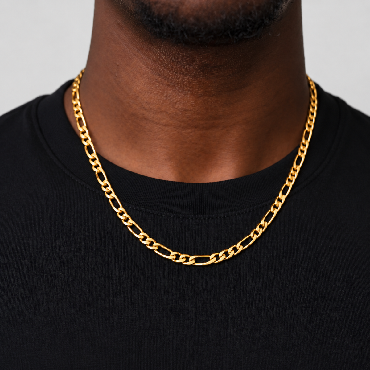 Unveiled 5mm Figaro chain in 18k PVD gold, 50cm, worn by the Unveiled model in a black cotton tee