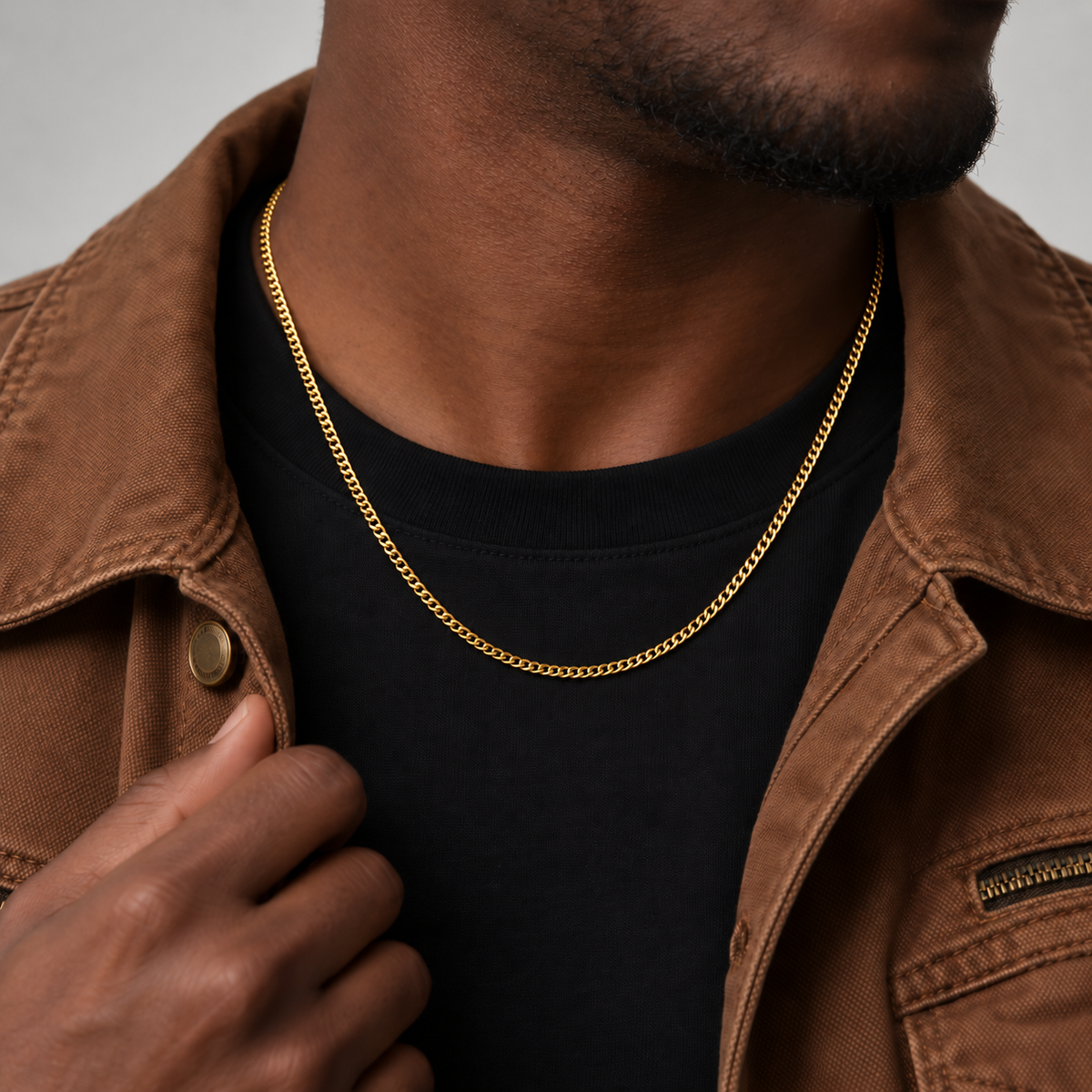 2mm Cuban chain in an 18k PVD gold finish, brown workwear jacket model photograph.