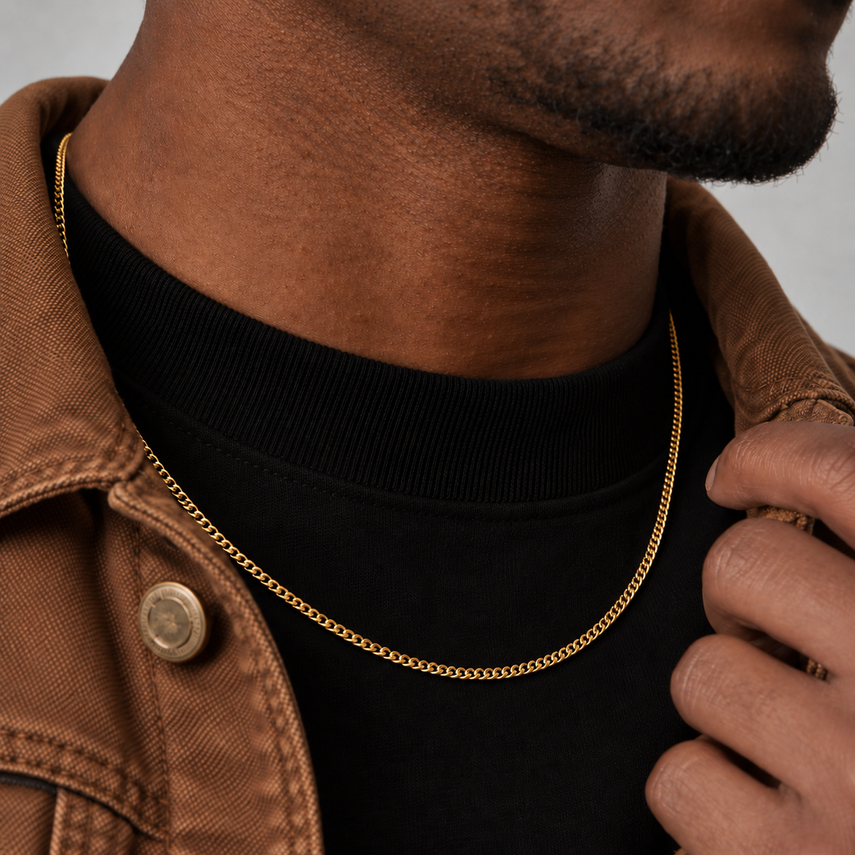 2mm Cuban chain in an 18k PVD gold finish, brown workwear jacket side view model photograph.
