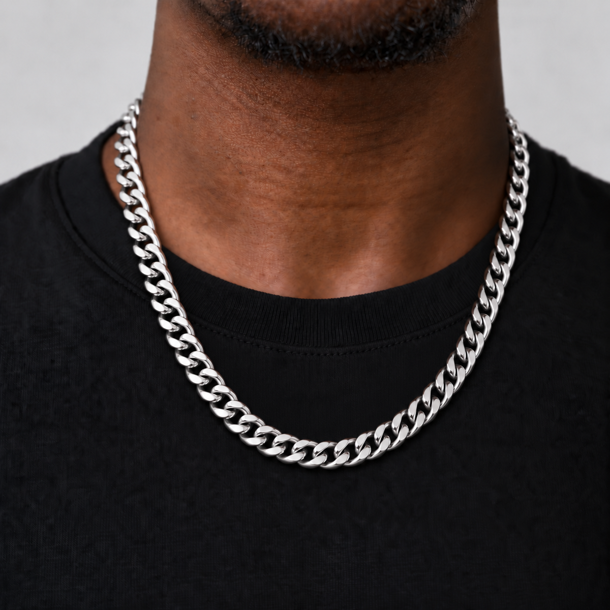 8mm silver Cuban chain, corrected 55cm upper-chest drop, black tee model photograph on Unveiled grey.