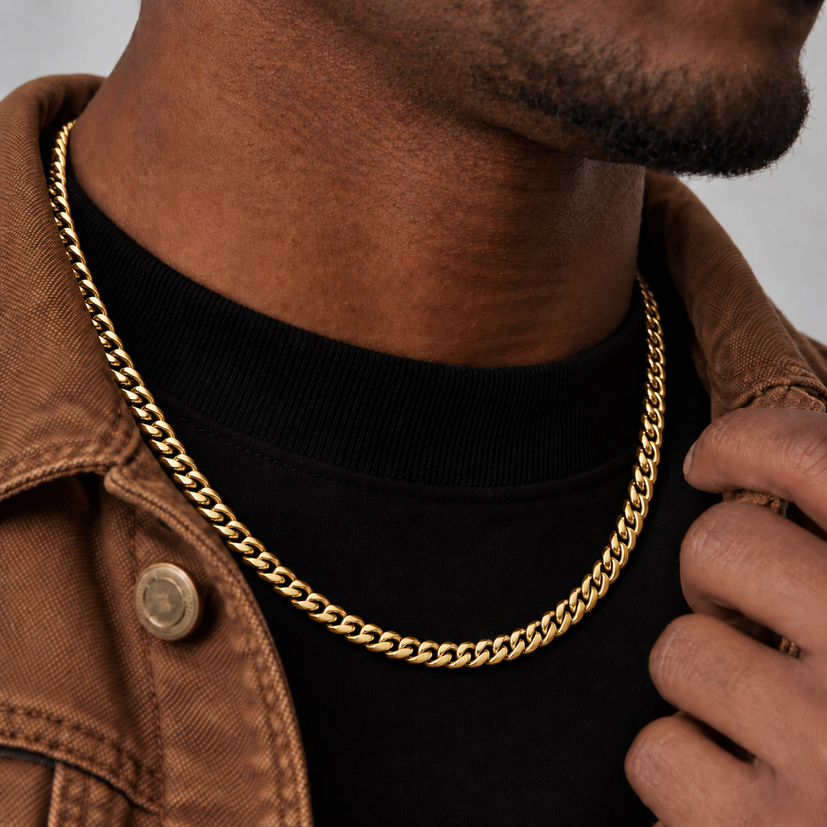 6mm 18k PVD gold Cuban chain, brown workwear side view, Unveiled website product photograph.