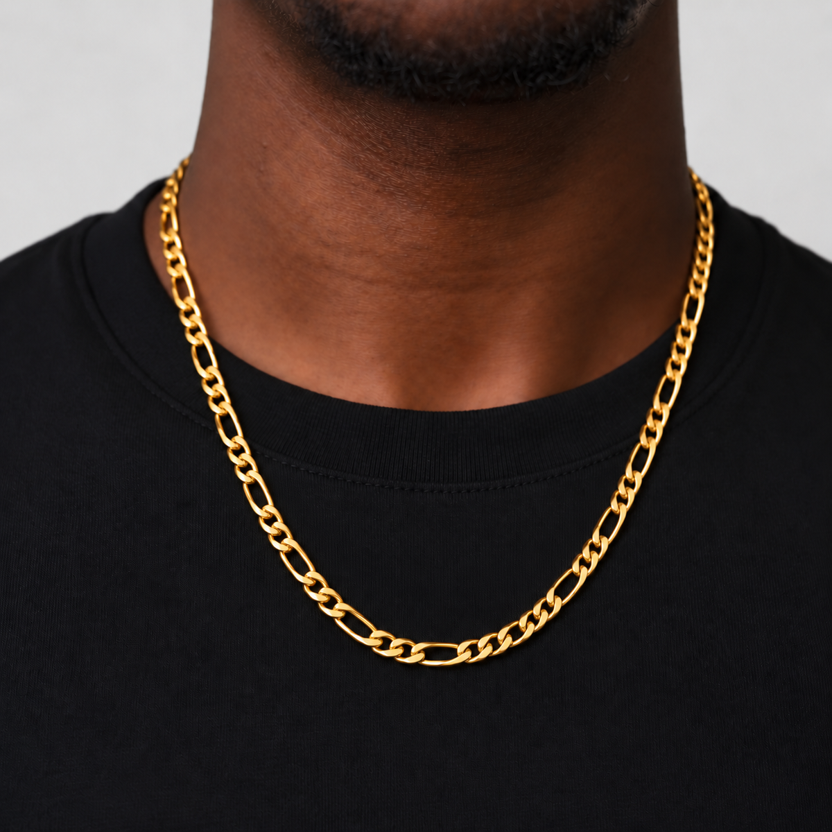 Unveiled 5mm Figaro chain in 18k PVD gold, 55cm, worn by the Unveiled model in a black cotton tee