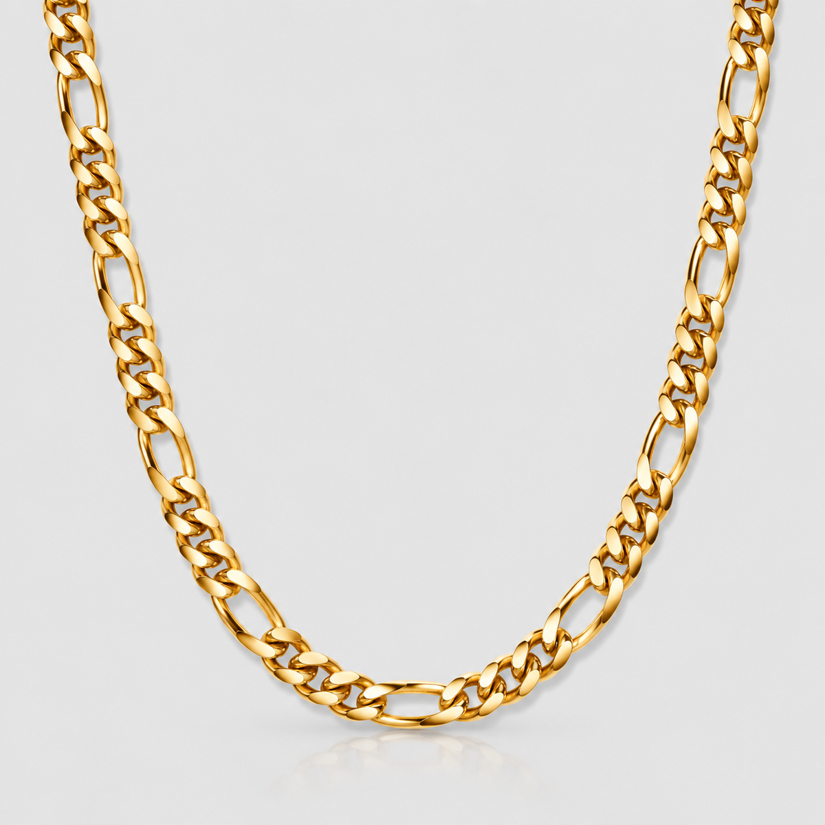 Unveiled 5mm Figaro chain in 18k PVD gold on a light grey studio background