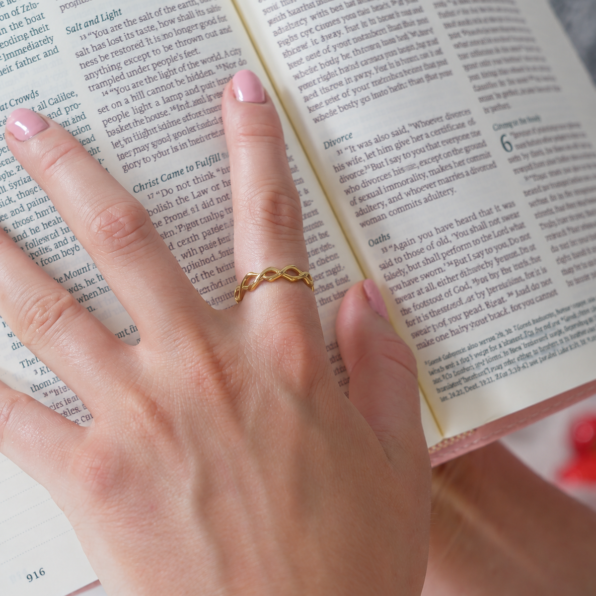 Dainty Crown of Thorns Ring in gold worn on a hand resting on an open Bible