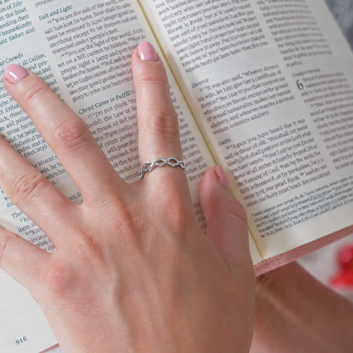 Dainty Crown of Thorns Ring in silver worn on a hand resting on an open Bible