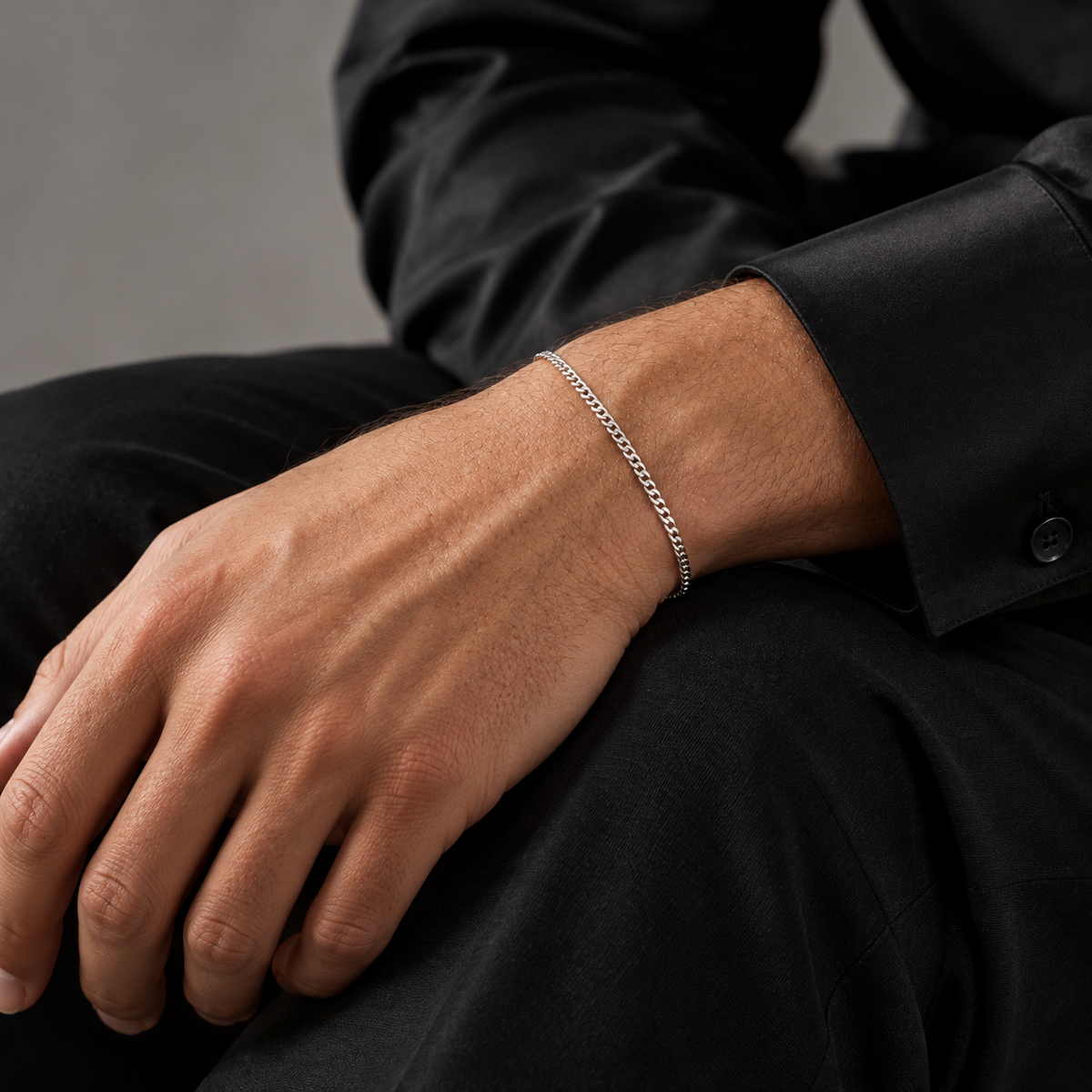 Silver 2mm Cuban bracelet worn with black silk, seated view