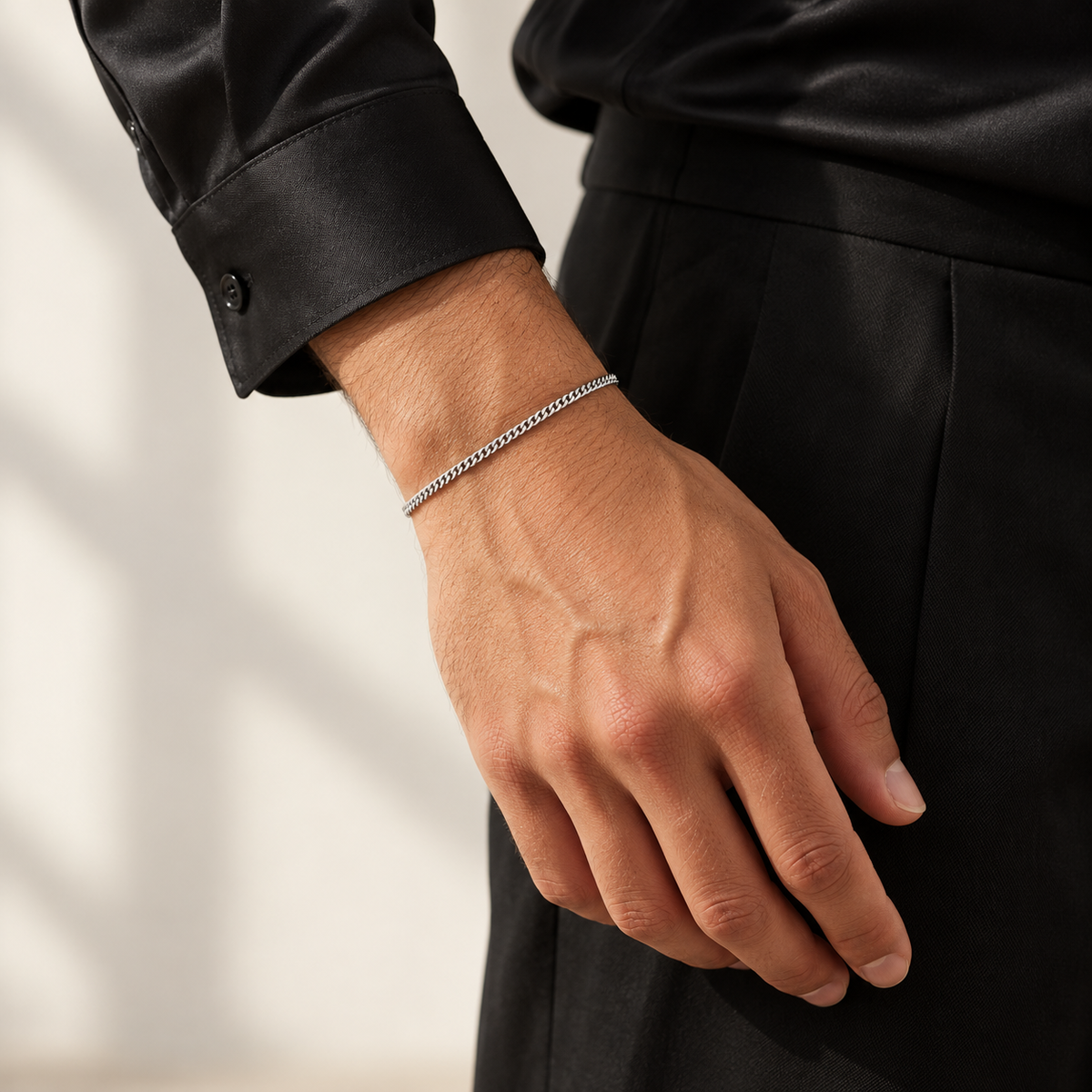 Silver 2mm Cuban bracelet worn with a black silk shirt, standing view