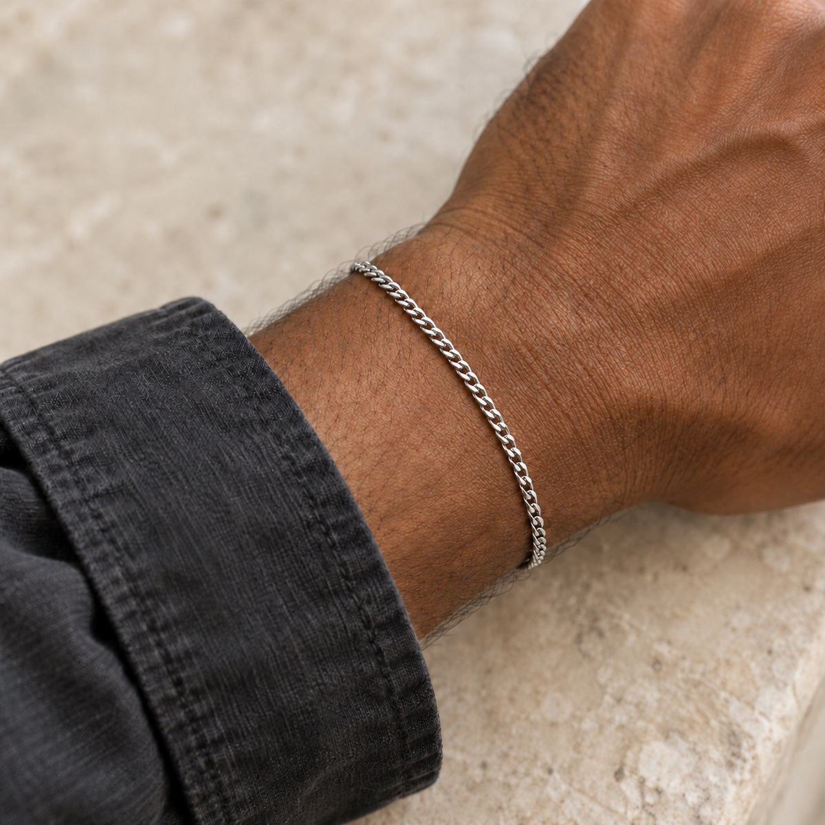 Silver 2mm Cuban bracelet beside a charcoal shirt cuff