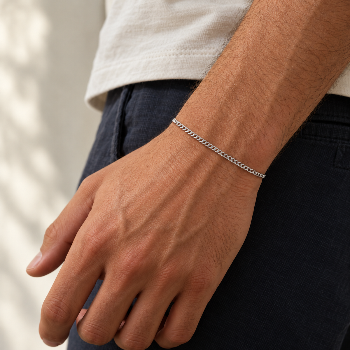 Silver 2mm Cuban bracelet on a relaxed wrist with a cream shirt